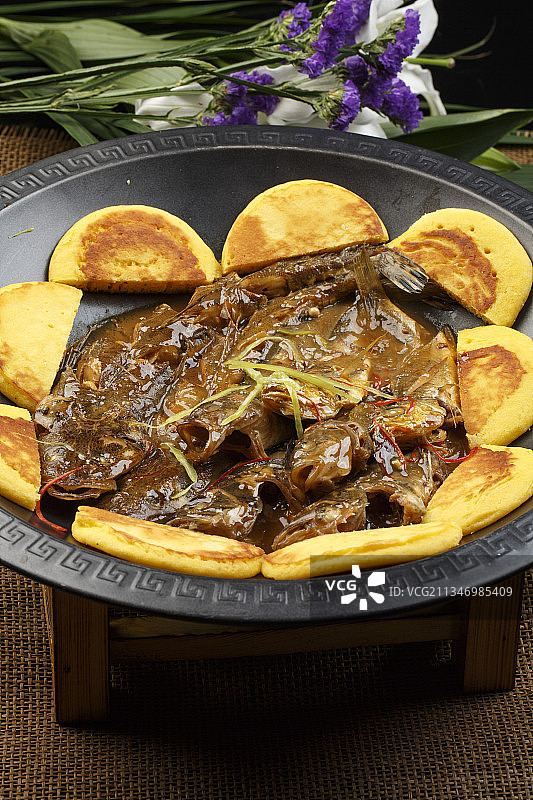 黑色铁锅装的垮炖杂鱼贴饼子图片素材