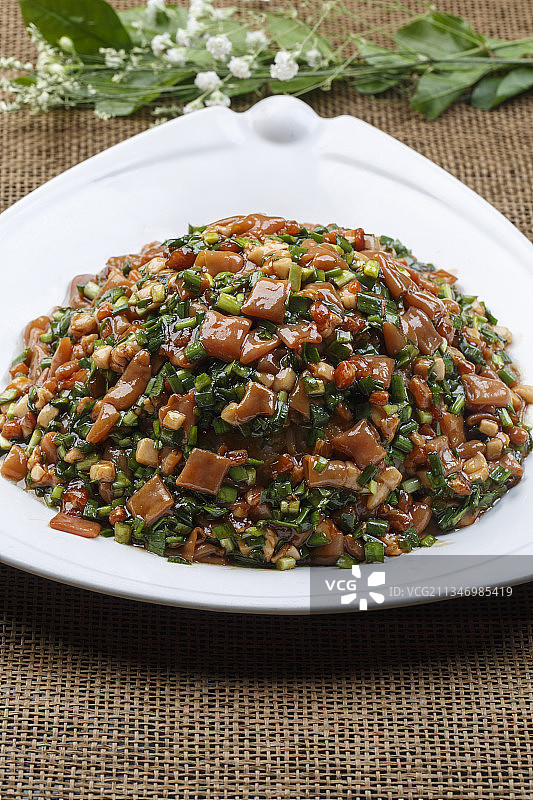 三角形白瓷盘装的韭菜炒海肠图片素材