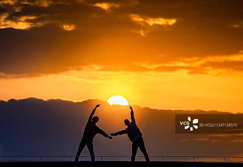 夕阳下人们在天空中跳跃的剪影图片素材