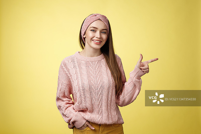 笑容满面的年轻女人在黄色背景下手势的肖像照图片素材