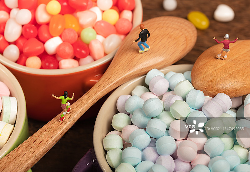 微缩创意木桌上的糖果碗与木勺上轮滑的青少年图片素材