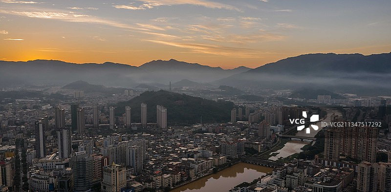 清晨的县城薄雾笼罩着建筑，天边镶嵌着桔色的朝霞，小河蜿蜒。图片素材