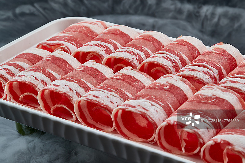 干冰缭绕的背景上摆放的草原肥羊肉卷图片素材