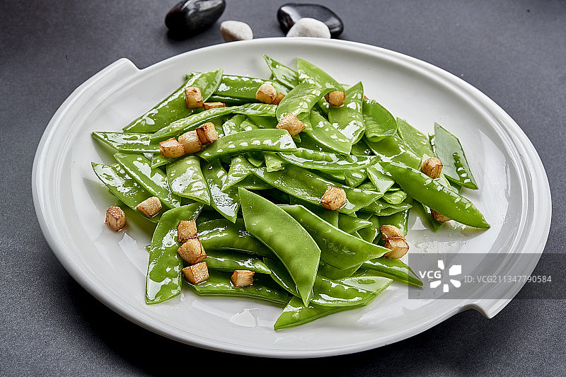 元瓷盘装的清炒时蔬蒜粒荷兰豆图片素材