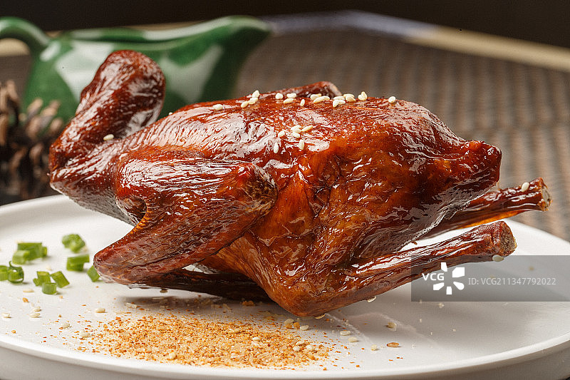 圆形白瓷盘装的港式脆皮乳鸽摆放在餐垫上图片素材