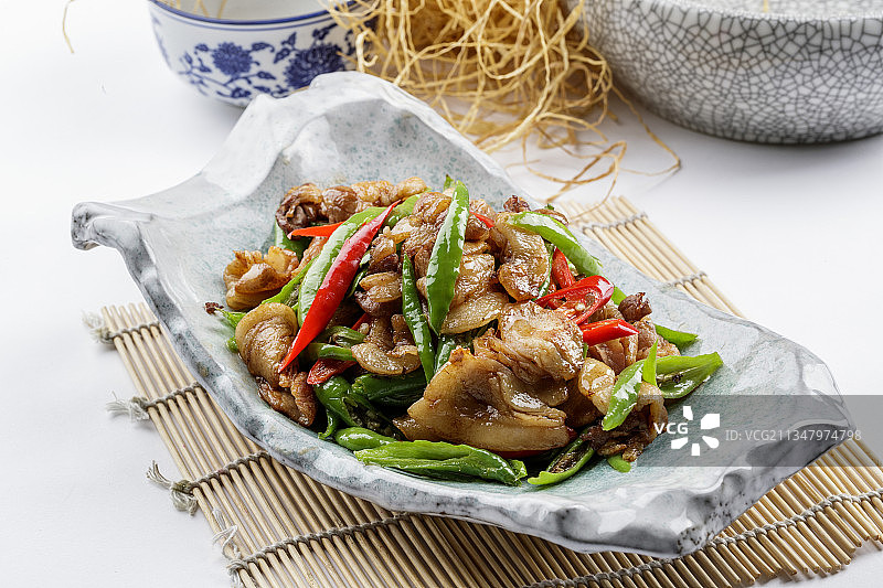 青瓷盘装的湘味小炒肉摆放在寿司帘上图片素材