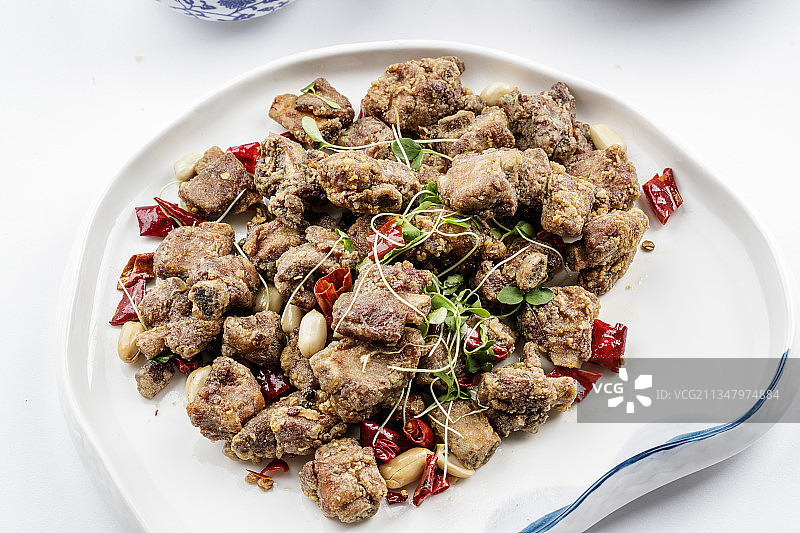 异形瓷盘装的香炸小排骨摆放在白色背景上图片素材