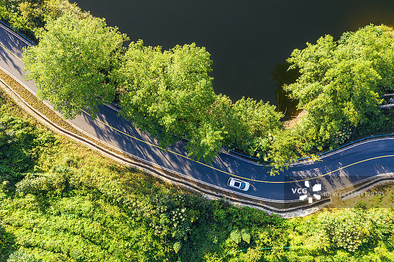 夏天日出时分的环湖公路上航拍行驶的汽车航拍图片素材