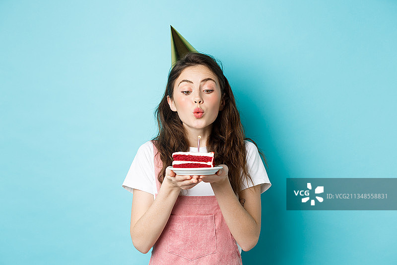 年轻女人吹生日纸杯蛋糕图片素材