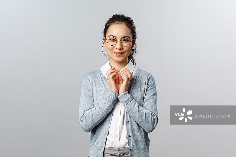 对着灰色背景微笑的年轻女人肖像图片素材