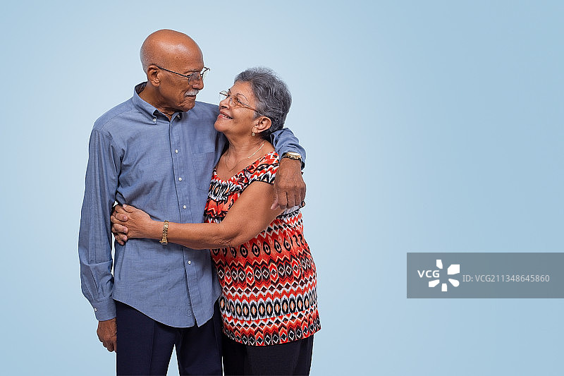 老年夫妇在蓝色背景前拥抱，古巴圣克拉拉图片素材