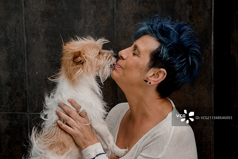 女人亲吻靠在墙上的纯种梗犬，西班牙拉斯帕尔马斯图片素材