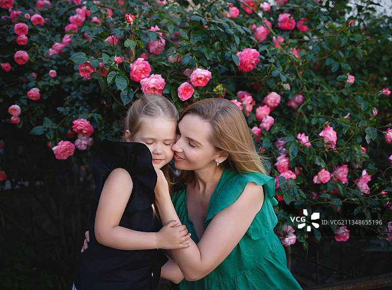 母亲和女儿在植物背景下拥抱图片素材