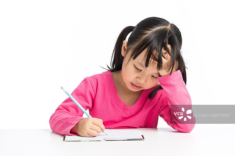 低头愁眉苦脸写作业的小学生图片素材