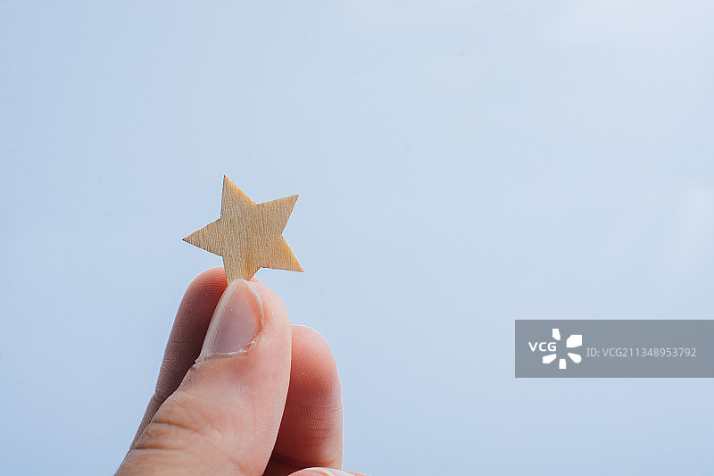 手持灰色背景上的小星星图片素材