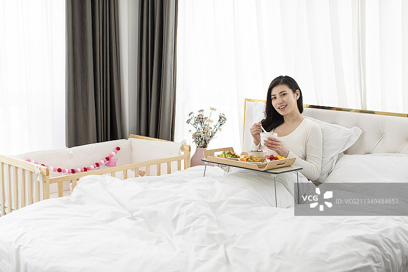 产妇在床上享受月子餐图片素材