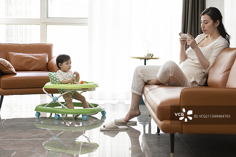 年轻妈妈玩手机而忽略宝宝图片素材