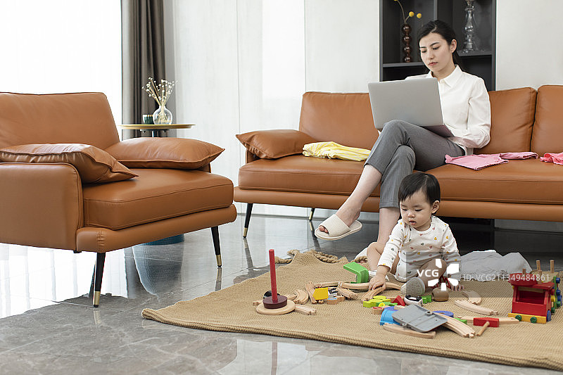 年轻妈妈在家忙工作而忽略宝宝图片素材