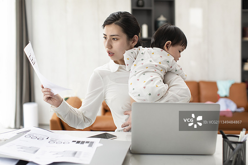 忙碌的妈妈在家边工作边照顾宝宝图片素材