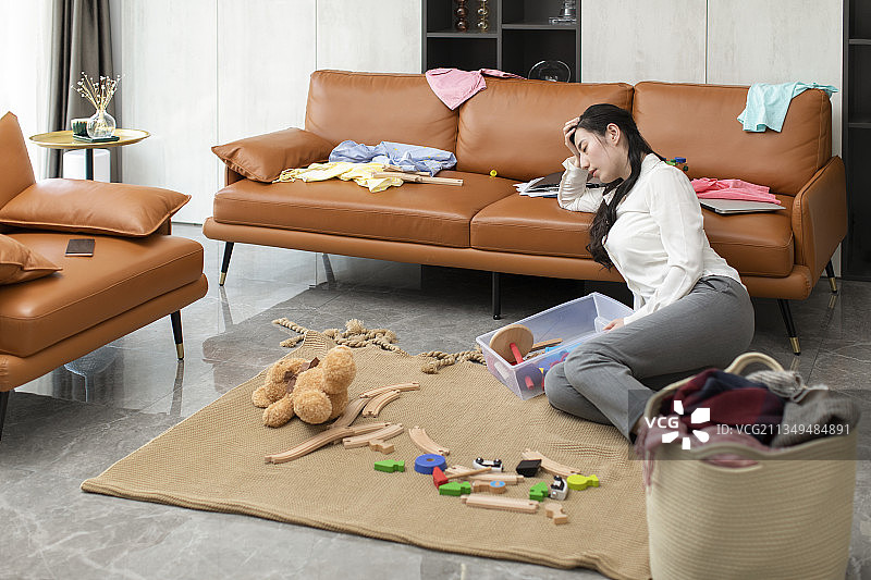 疲倦的妈妈收拾凌乱的客厅图片素材