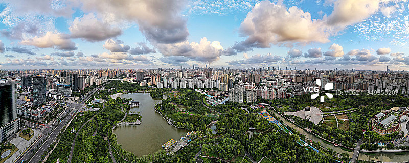 全景航拍蓝天白云下上海大宁灵石公园及远处的城市天际线图片素材