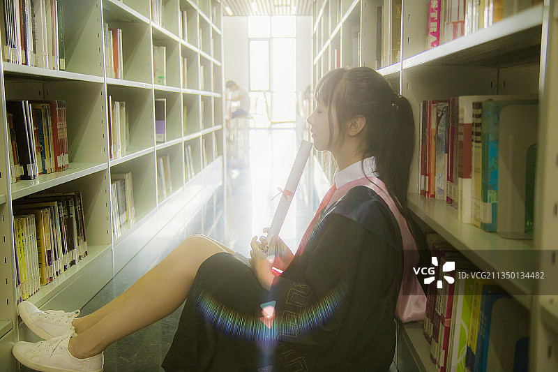 图书馆内穿着学士服的女孩图片素材