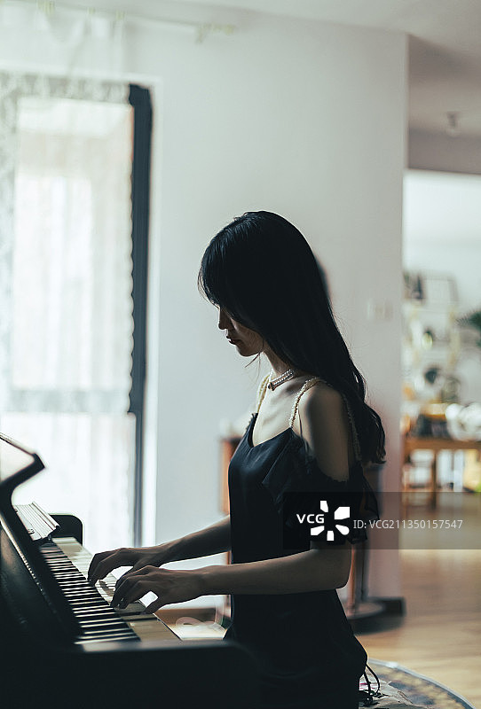 室内穿着黑色连衣裙弹钢琴的女孩图片素材