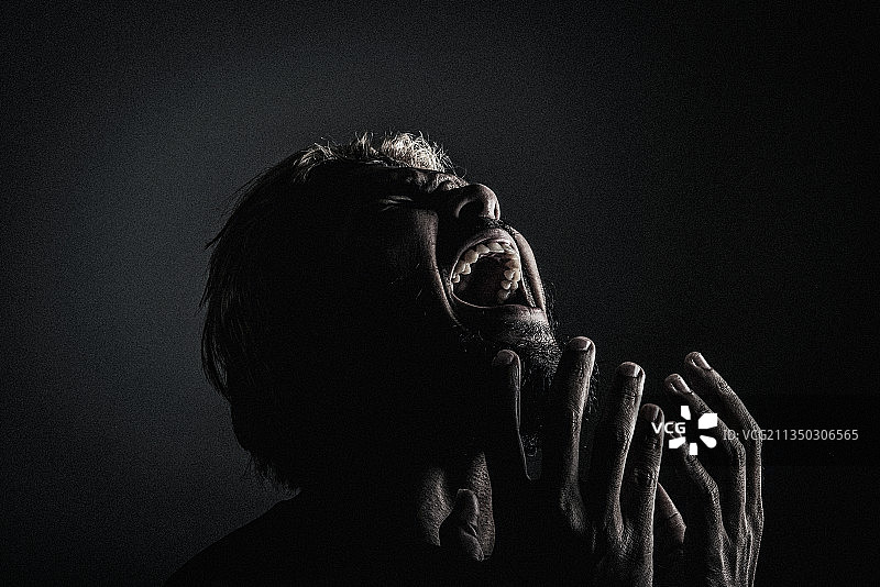 男人对着黑色背景哭喊特写图片素材