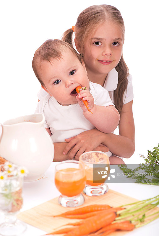 女孩和小男孩喝胡萝卜汁白色背景图片素材