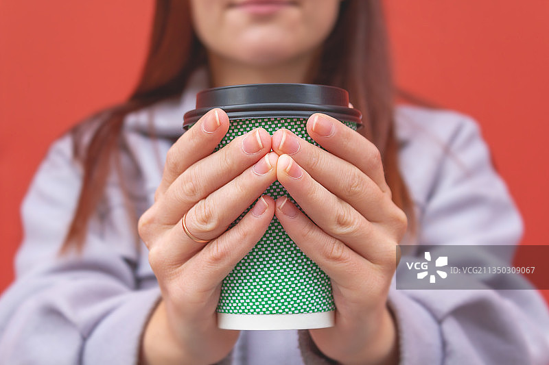 红色背景下，女人拿着饮料的身体中部照片图片素材