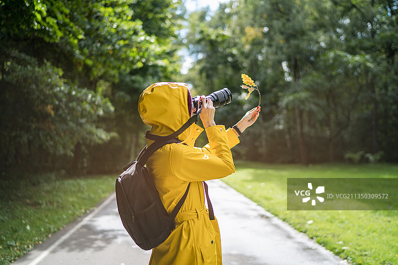 身穿黄色外套的自然摄影师在拍照图片素材