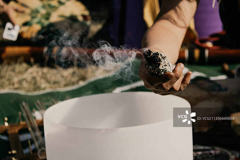 手持鼠尾草在颂钵上熏香的女人图片素材