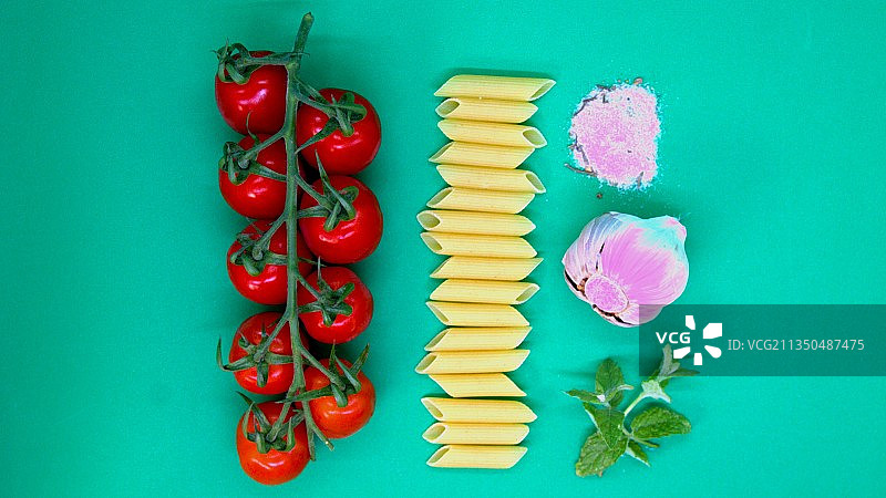 蓝绿色背景上带配料的未煮意大利面俯视图图片素材