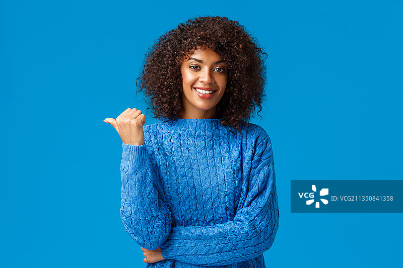 微笑的年轻女人在蓝色背景前做手势图片素材
