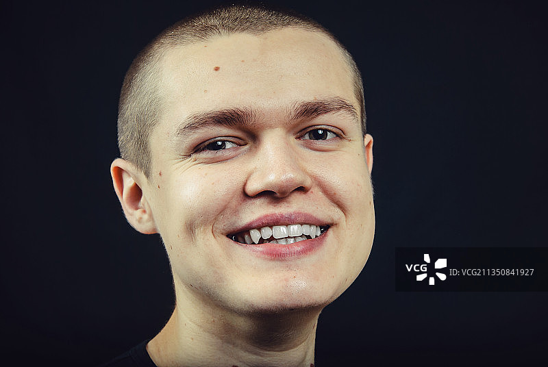 微笑的年轻男子在黑色背景前的肖像，乌克兰哈尔科夫图片素材