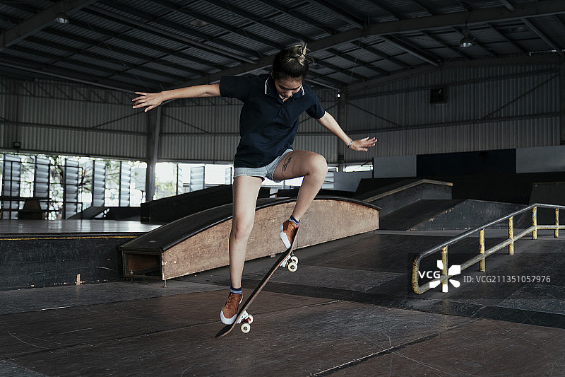 一名身穿深蓝色衬衫和短牛仔裤的女子一边练习跳水，一边用长板跳。图片素材