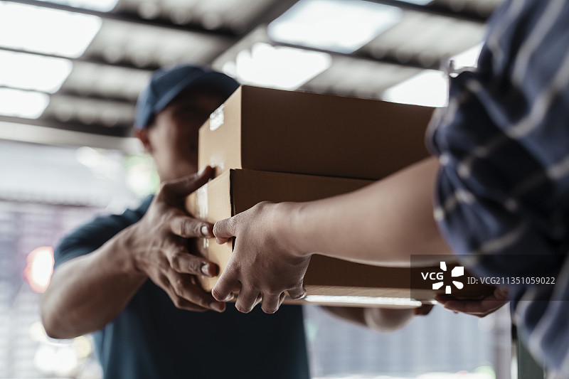 当地的快递员在值班，将纸板箱送到客户家中。图片素材