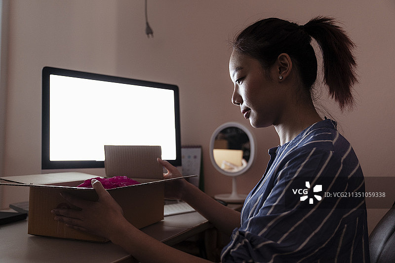 亚洲女人在房间电脑前打开货运箱-送货服务理念。图片素材