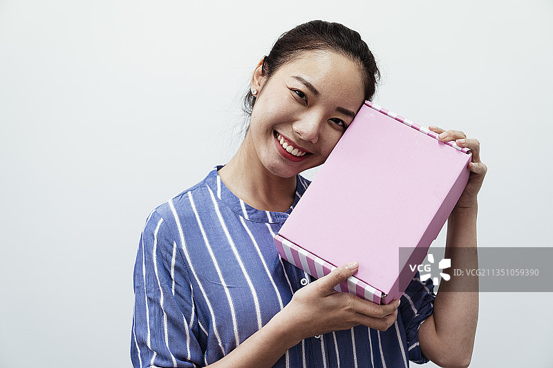 欢快快乐的亚洲泰国女人拿着粉红色的礼盒孤立在白色的背景上。图片素材