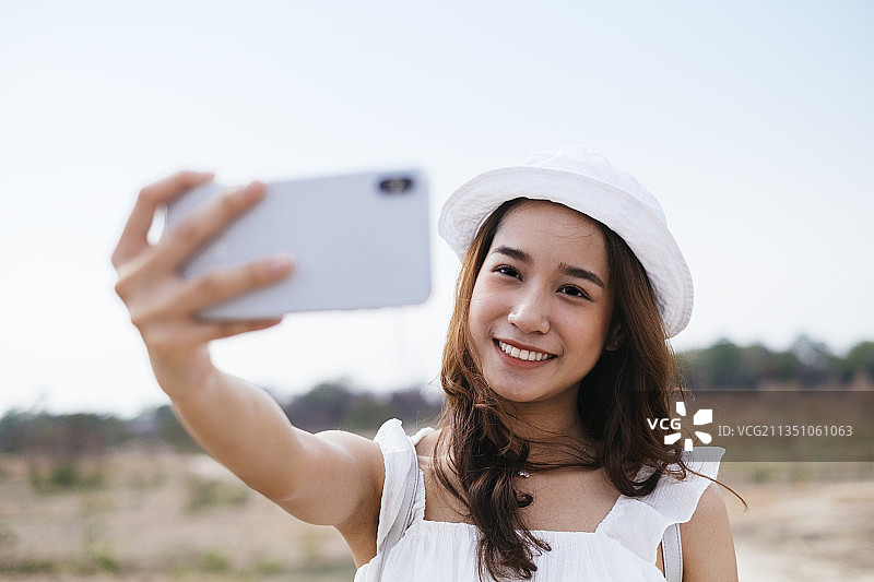 美丽的亚洲泰国女旅行者的近距离肖像与智能手机自拍或录制视频youtube。图片素材