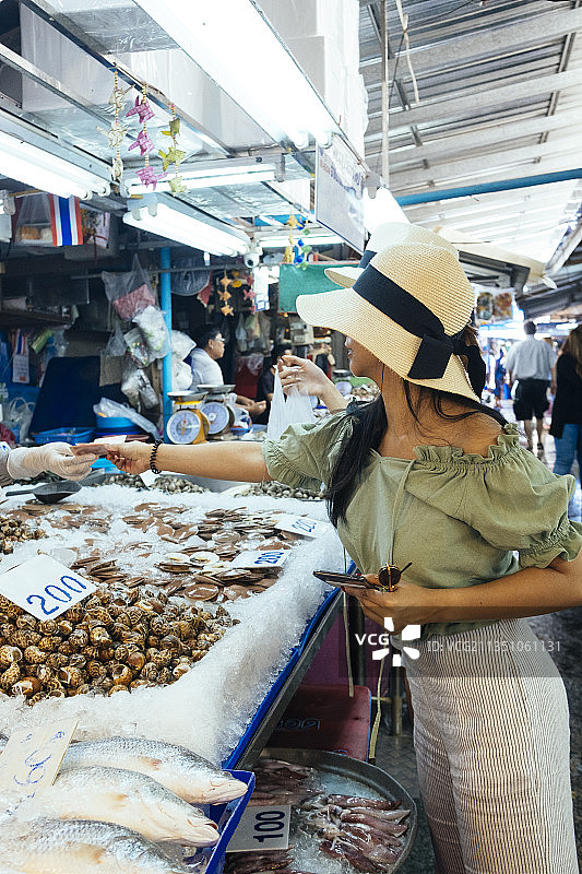 美丽的亚洲游客在泰国当地市场寻找海鲜。图片素材