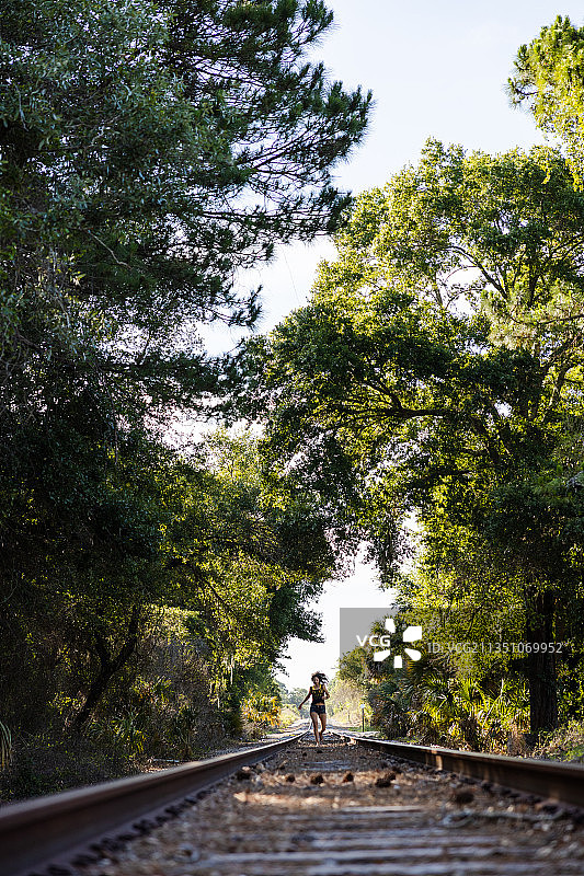 快乐的年轻女人在美国佛罗里达州盖恩斯维尔的铁轨上玩耍图片素材