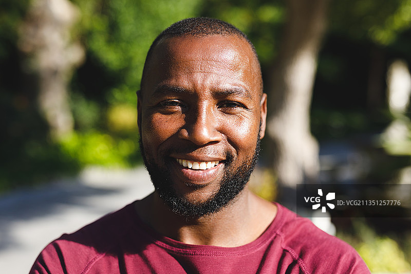 阳光明媚的花园里，微笑看着镜头的非洲裔美国男子图片素材
