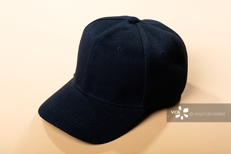 浅棕色背景上的传统黑色棒球帽图片素材