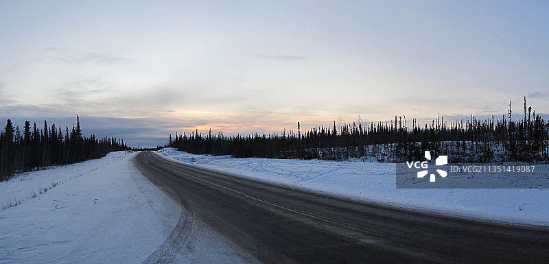 加拿大西北地区日落时分，白雪皑皑的景观中的空旷道路图片素材