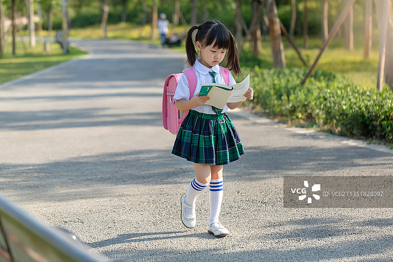 背着书包边走边看书的小学生图片素材