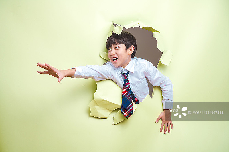 小男孩穿过破碎的纸洞图片素材