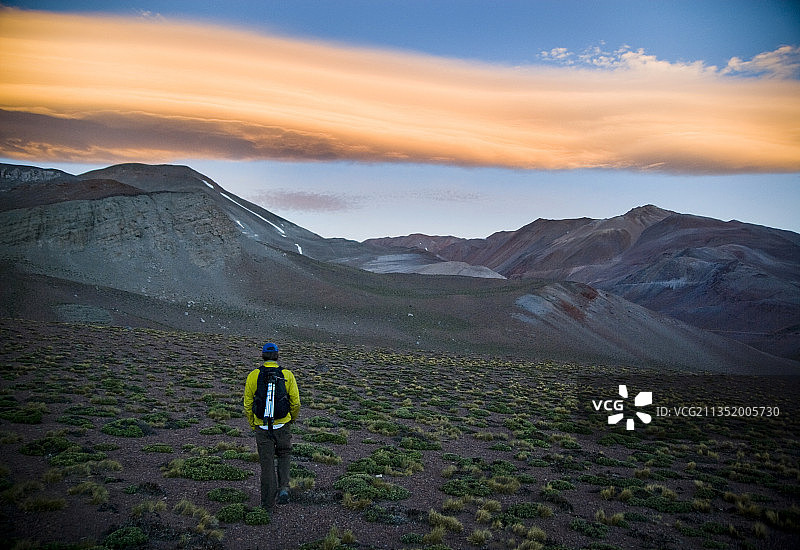 在智利北部，男人在黄昏时分走过沙漠，天空色彩斑斓。图片素材