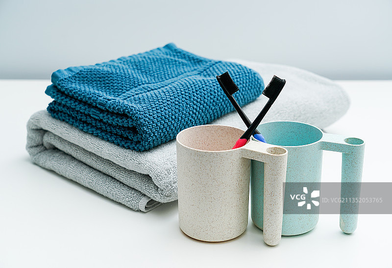 情侣款牙刷漱口杯洗漱用具毛巾放在白色桌面上图片素材