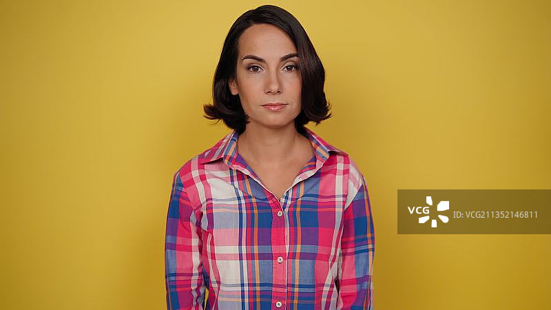 站在黄色背景上的年轻女子肖像图片素材